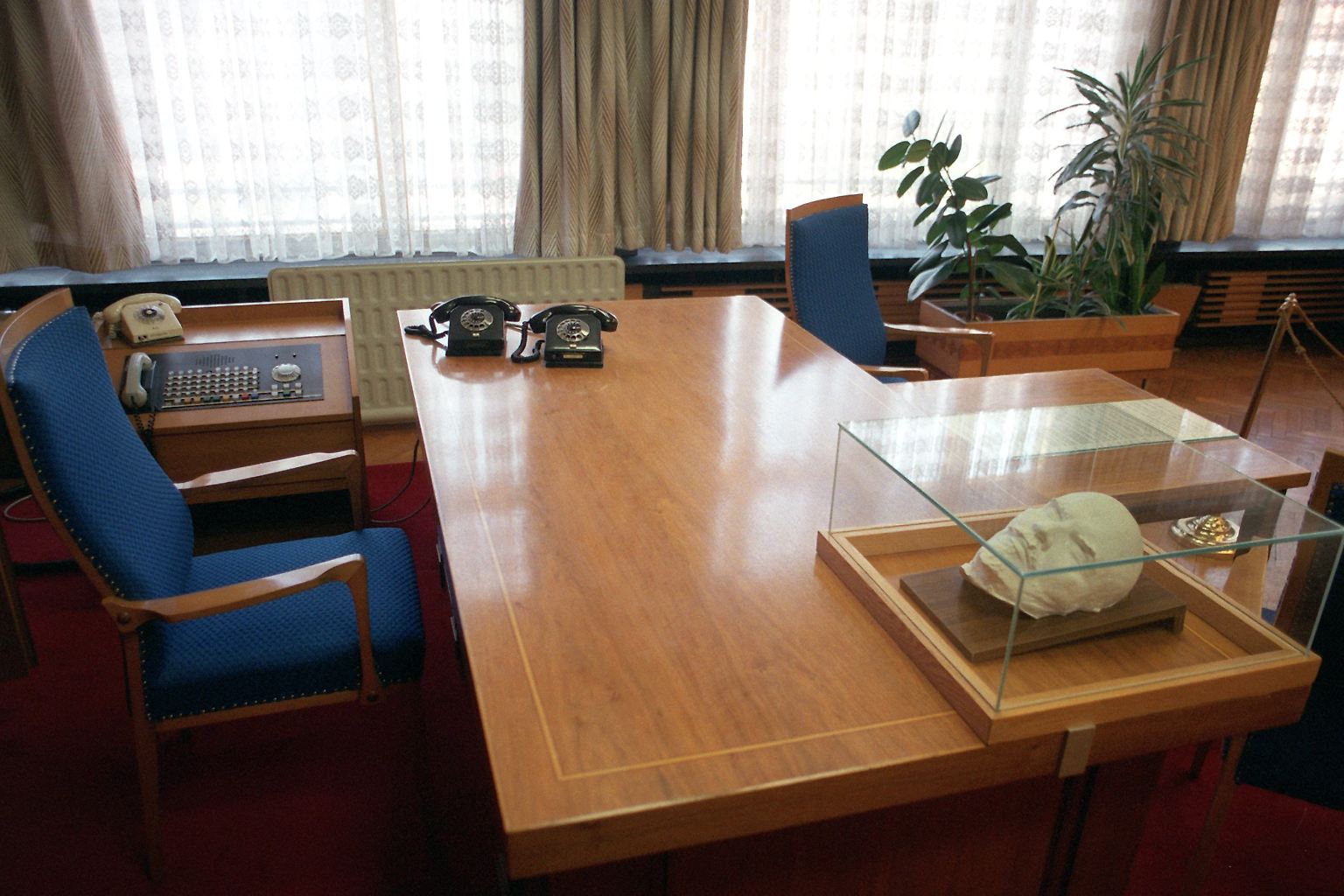 Das Büro des meistgefürchteten Mannes der DDR wirkt fast gemütlich: Fischgrätparkett, Holzmöbel und vertäfelte Schränke, kobaltblau bezogene Lehnstühle und Blümchengardinen. 