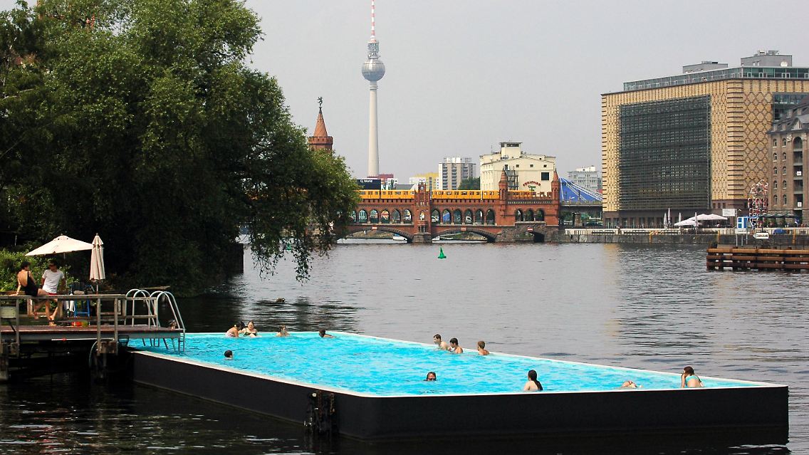 Vor der Kulisse von Fernsehturm und Oberbaumbrücke vergnügen sich Gäste im Badeschiff im Bezirk Treptow.