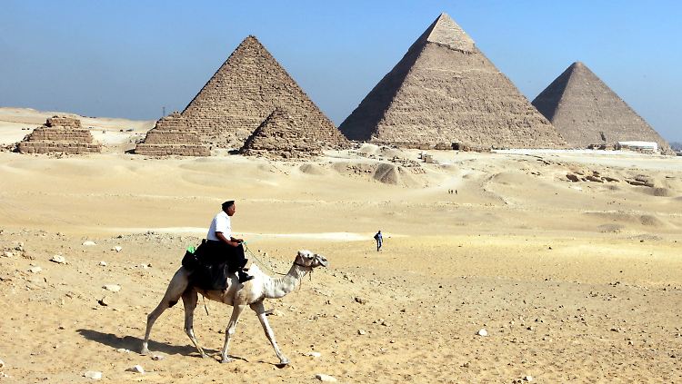 Ein ägyptischer Polizist auf einem Kamel geht vor den Pyramiden von Gizeh auf Streife.