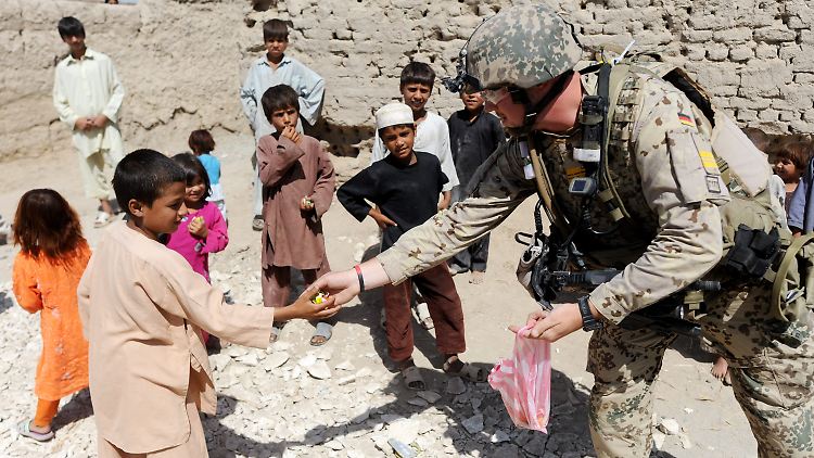 Bundeswehrsoldaten verteilen Bonbons an afghanische Kinder.
