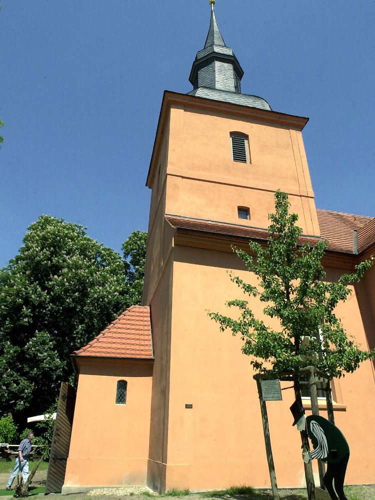 Erinnerung: Die Pfarrkirche von Ribbeck mit einem neu gepflanzten Birnbaum. Eine Holzfigur am Baum erinnert an den Herrn von Ribbeck zu Ribbeck im Havelland.