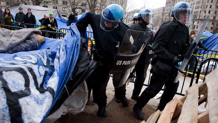 Polizisten bauen die Zelte ab.