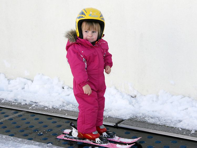 Mit einem Förderband werden kleine Skianfänger nach oben befördert.