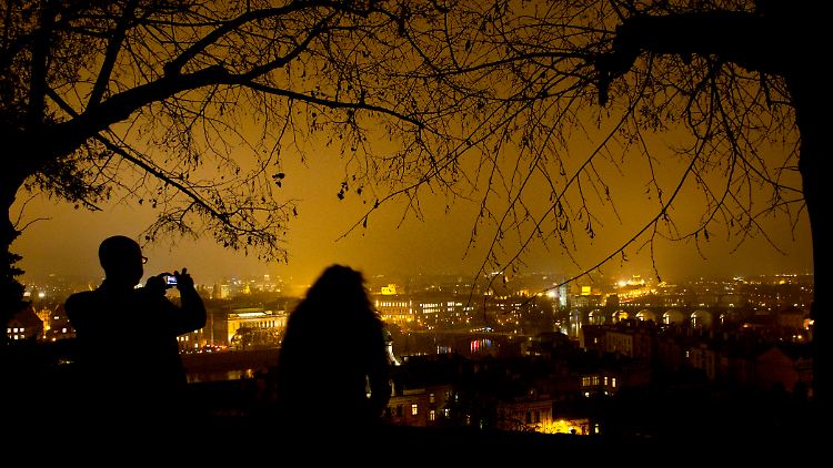 Goldene Stadt bei Nacht: Touristen auf einem Hügel über Prag.