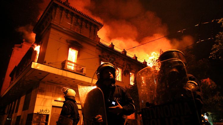 Polizisten vor einem brennenden Gebäude in Athen.