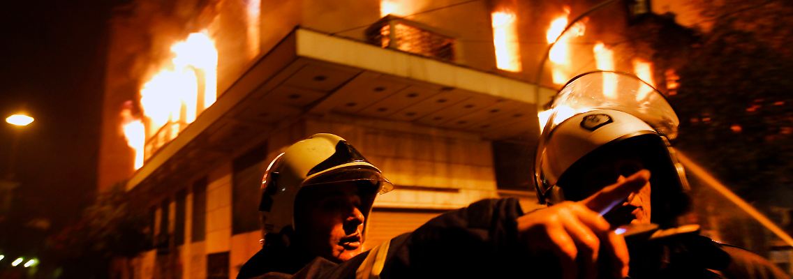 Feuerwehrleute vor einem brennenden Gebäude in Athen.