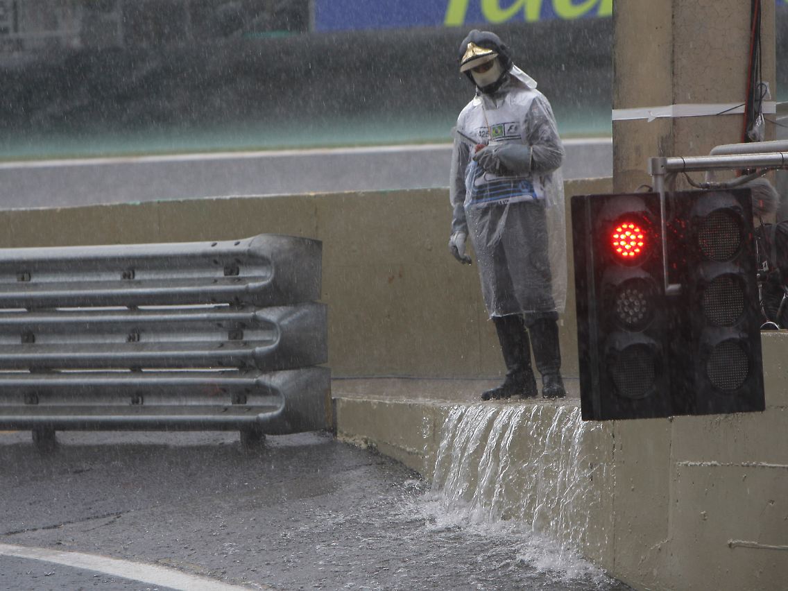 Ein Feuerwehrmann wartet im strömenden Regen an der Strecke.