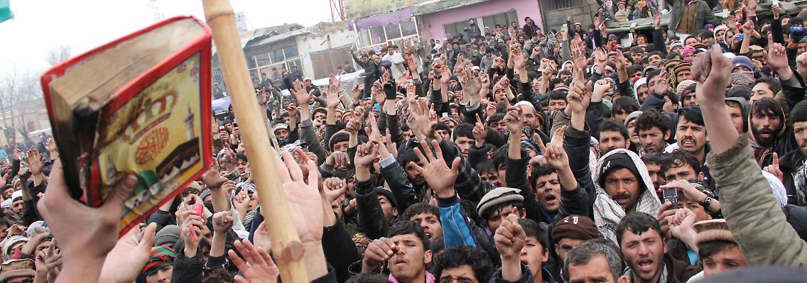 Vor dem Stützpunkt in Bagram hält ein Afghane einen Koran in die Luft, der von US-Soldaten angezündet worden sein soll.