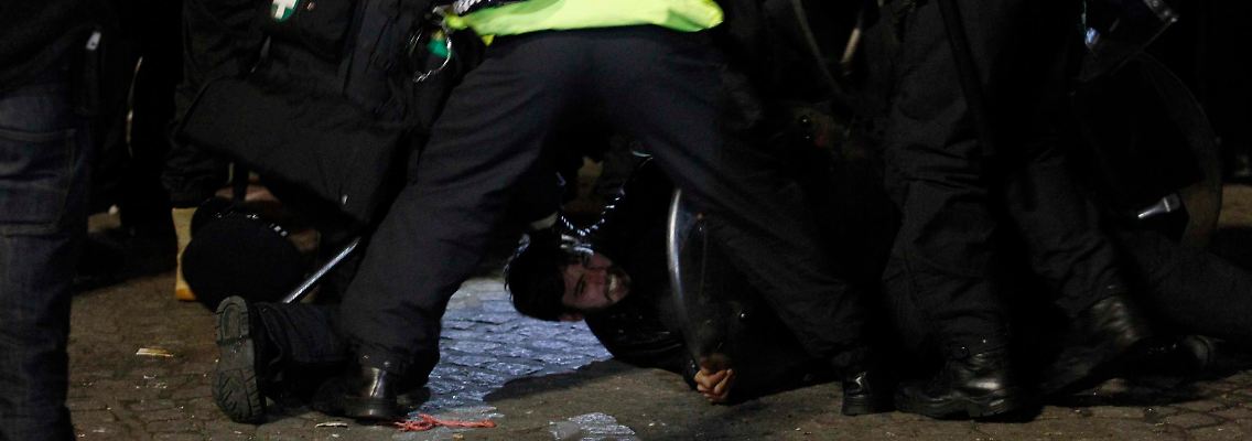 Polizisten tragen einen Demonstranten weg.