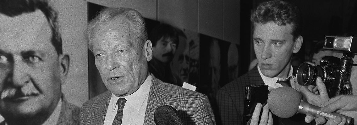 23. März 1987: Willy Brandt hat soeben seinen Rückzug vom Parteivorsitz verkündet. Nun wird er von Reportern bestürmt.