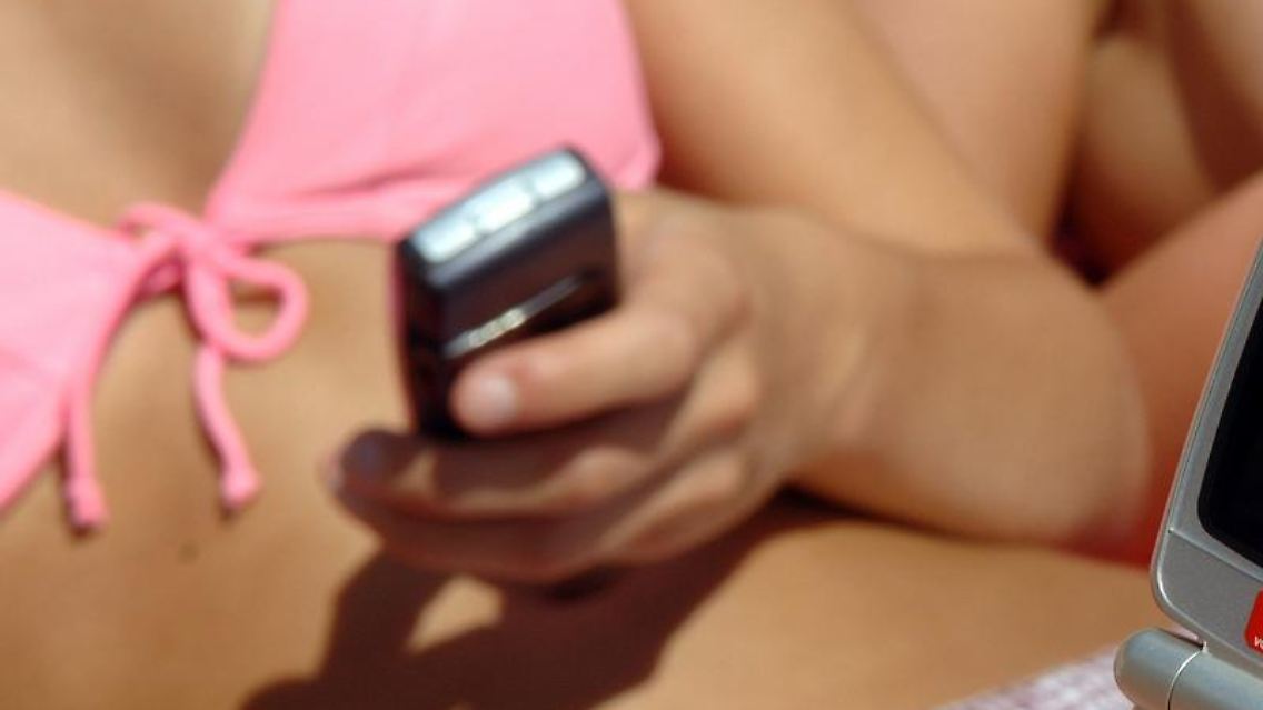 Mit dem Handy am Strand: Für das Internet-Surfen im europäischen Ausland gibt es ab Juli Obergrenzen. Foto: Patrick Pleul