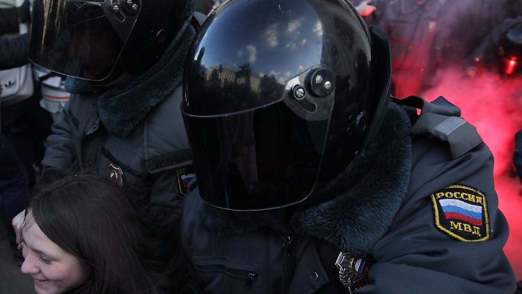 Russische Polizisten nehmen eine Demonstrantin fest - mit verdunkeltem Motorradhelm.