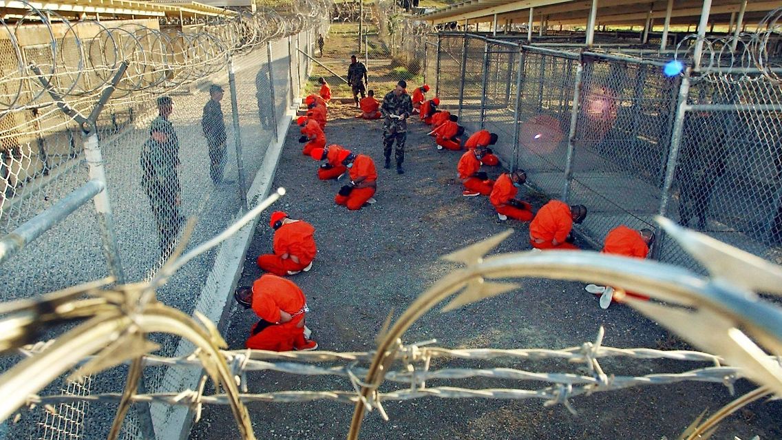 In orangefarbene Overalls gekleidete Häftlinge knien im Camp X-Ray auf dem US-Marinestützpunkt Guantanamo Bay auf Kuba (Archivbild von 2002).