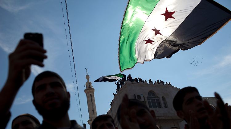 Protest gegen das Assad-Regime im Norden Syriens. Demonstranten schwenken die Flagge des Widerstands durch die Luft.