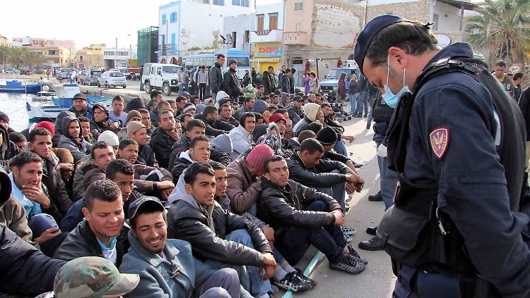 Ein italienischer Polizist bewacht in Lampedusa Flüchtlinge aus Nordafrika.
