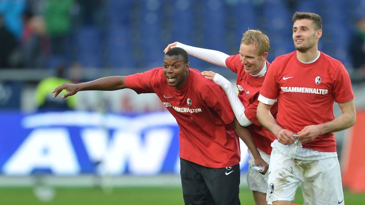 Die Freiburger Fallou Diagne (l-r), Markus Rosenthal und vorne Ivan Santini freuen sich nach Spielende über den Punkt, der dem SC den Klassenerhalt sichert.