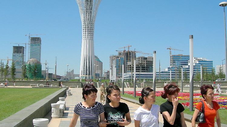 Touristinnen vor dem Baiterek-Turm in der kasachischen Hauptstadt Astana; hinten links die Zwillingsbürotürme von Frank Gehry.