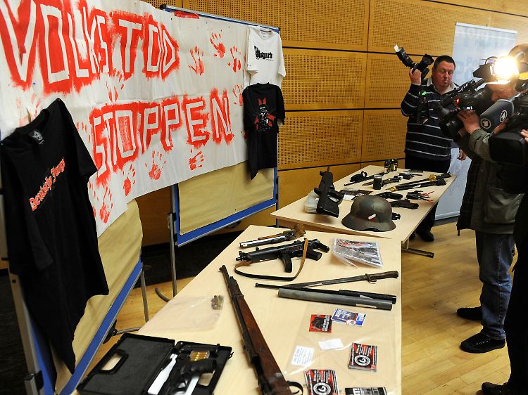 Die Polizei präsentiert die gefundenen Waffen - und ein Transparent mit der Aufschrift "Volkstod stoppen".