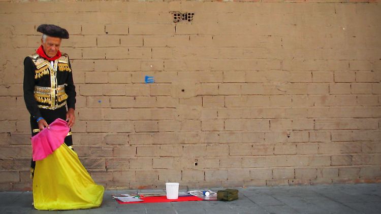Ein alter Spanier imitiert einen Stierkämpfer und hofft auf Spenden.
