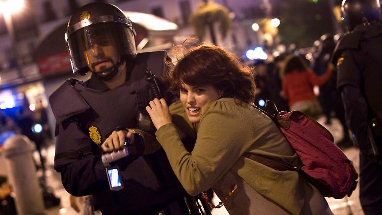 Ein Polizist versucht, eine Demonstrantin vom Puerta del Sol abzuführen.
