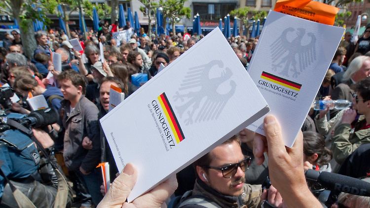 Mit in die Höhe gehaltenen Grundgesetzen wollen die Demonstranten auf ihr Recht auf Versammlungsfreiheit aufmerksam machen.