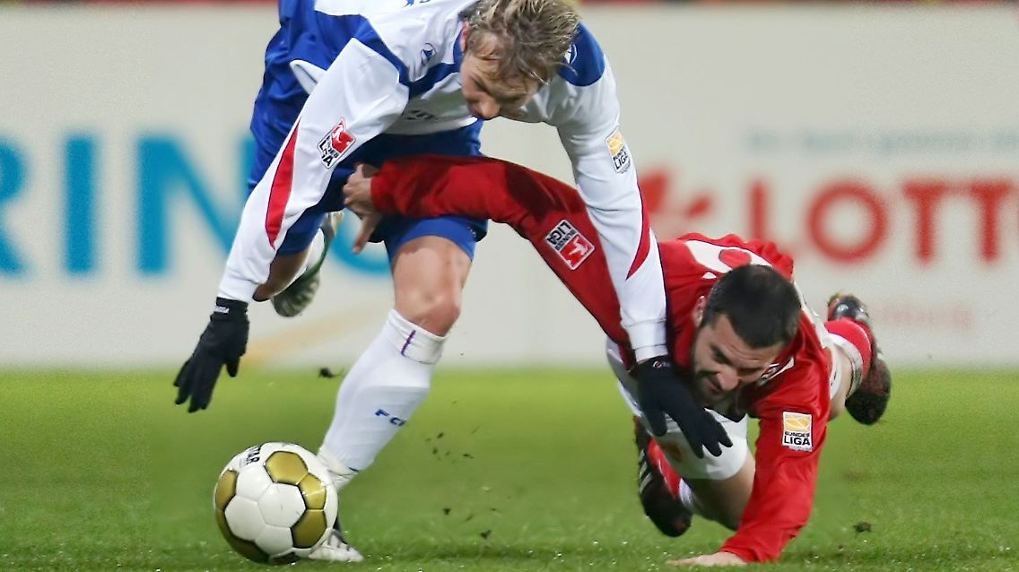 Der Cottbuser Stiven Rivic (r) und Rostocks Kevin Schöneberg im gemeinsamen Sturz beim Kampf um den Ball.