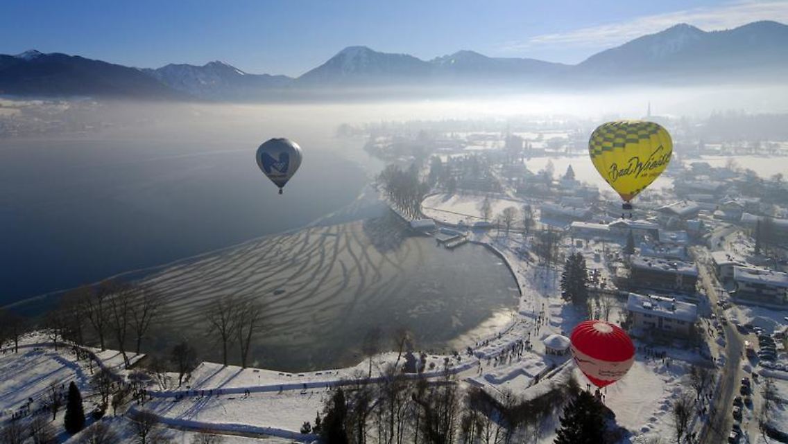 Bunte Tupfer am Himmel: Die Alpengipfel bilden die Kulisse für die Montgolfiade Ende Januar am Tegernsee in Oberbayern.