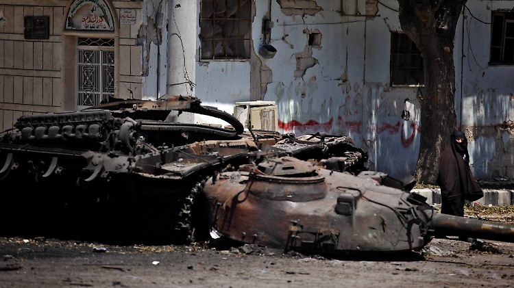 Eine Frau läuft bei Idlib an einem zerstörtem Panzer vorbei.