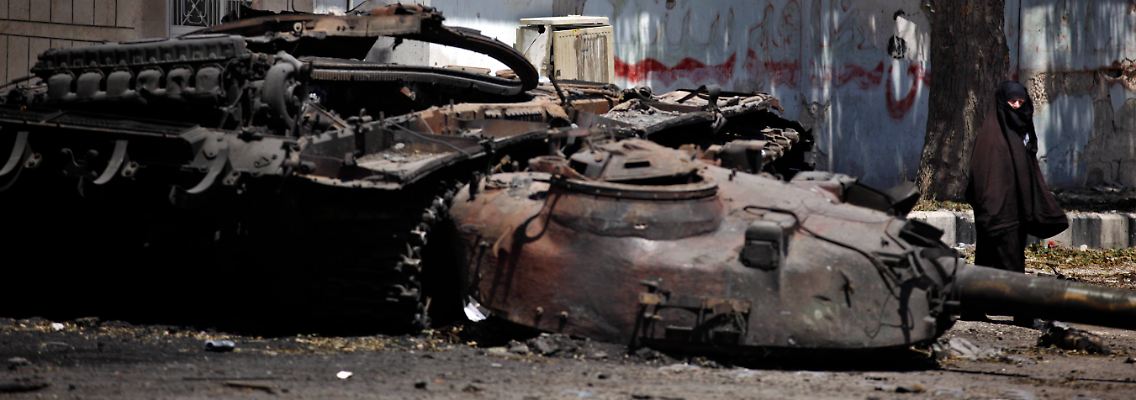 Eine Frau läuft bei Idlib an einem zerstörtem Panzer vorbei.