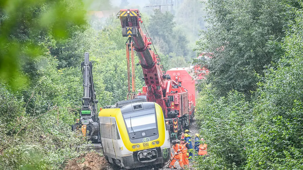 Mit-einem-Kran-wird-an-der-Unfallstelle-an-der-ein-Regionalzug-entgleist-ist-gearbeitet-Ein-Regionalexpress-war-am-Sonntagabend-27-07-2025-in-Riedlingen-nach-bisherigen-Erkenntnissen-infolge-eines-Hangrutsches-entgleist