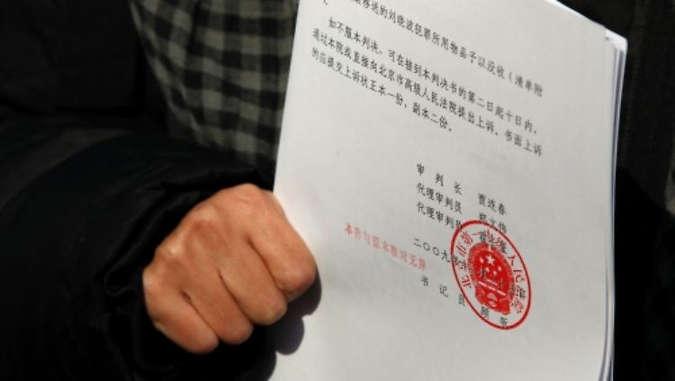Liu Xia, die Frau des Bürgerrechtlers, hält nach dem Prozess das Urteil in der Hand.