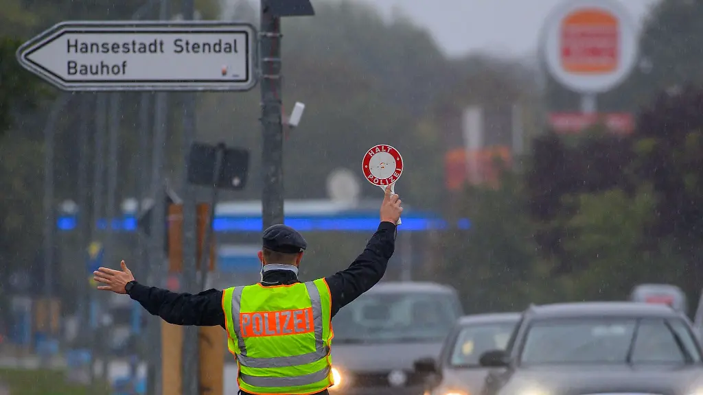 Ein-Polizist-winkt-mit-einer-Polizeikelle-einen-Autofahrer-aus-dem-Strassenverkehr