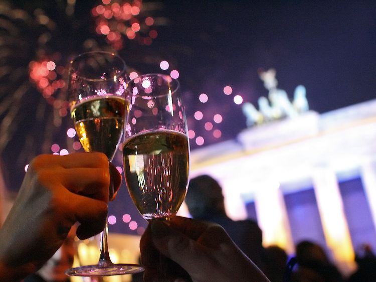 Ein Pärchen stößt vor der Quadriga am Brandenburger Tor in Berlin mit Sekt auf das neue Jahr an.