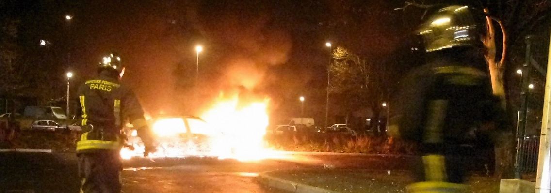 Feuerwehrleute versuchen in der Nacht zum 01.01.2009 ein von Randalierern angezündetes Auto in La Corneuve bei Paris zu löschen.