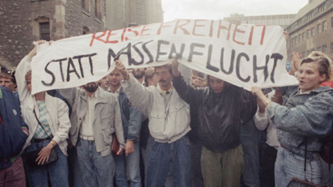 Am 4. September 1989 findet die erste Montagsdemonstration in Leipzig statt. Die Demonstranten rufen "Wir wollen raus", aber auch "Wir bleiben hier".