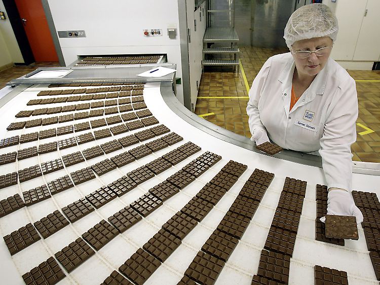 Eine Ritter Sport-Mitarbeiterin kontrolliert in der Produktion in Waldenbuch Schokoladen-Tafeln.