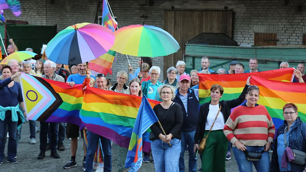 Menschen-mit-Regenbogenflaggen-und-schirmen-beteiligten-sich-an-einer-Kundgebung