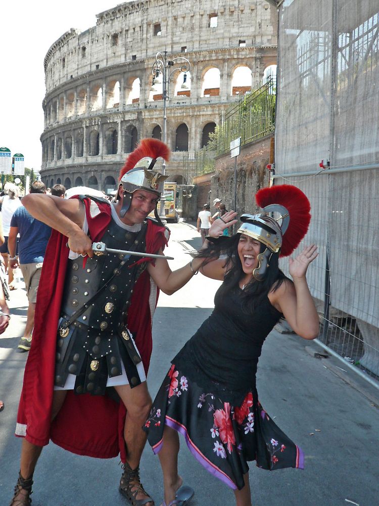 Ein Mann posiert in der Uniform eines römischen Legionärs mit einer Touristin vor dem Kolosseum.