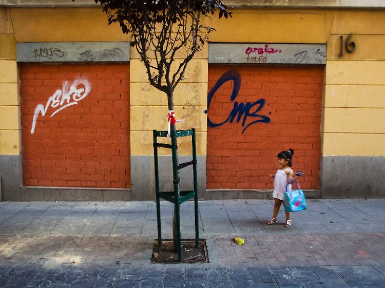 Zeichen der Krise: Ein Mädchen steht in Madrid vor einem Geschäft, dessen Eingang zugemauert wurde.