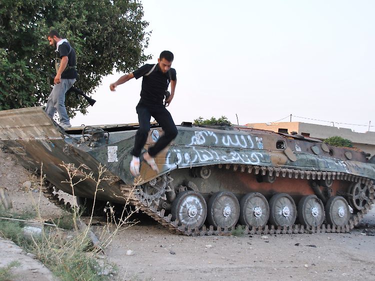 Rebellen inspizieren einen zerstörten Panzer.