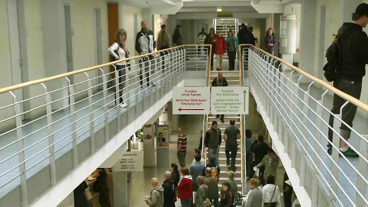 Im Gebäude der Arbeitsagentur in Leipzig stehen Frauen und Männer an den Schaltern für die Vermittlung zu den verschiedenen Bereichen.