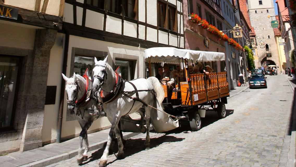 Hand auf dem Geldbeutel: Der Eurokurs ist für außereuropäische Besucher zurzeit eher ungünstig. (Touristen in Rothenburg ob der Tauber)