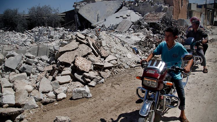 Jugendliche betrachten die Zerstörungen in Aleppo.
