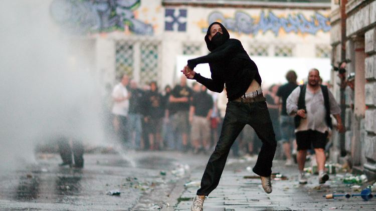 Ein Demonstrant wirft einen Stein in Richtung von Polizisten. Insgesamt verläuft das Schanzenfest glimpflich.