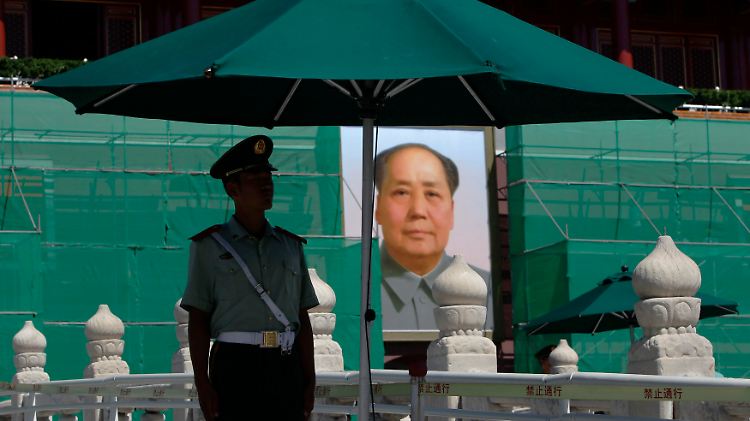 Eine Wache steht vor einem Mao-Bild in Peking.