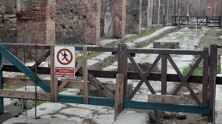 Eine durch eine Absperrung gesicherte Straße in Pompeji, an dem ein Schild mit der Aufschrift "Zutritt verboten" geschrieben ist 