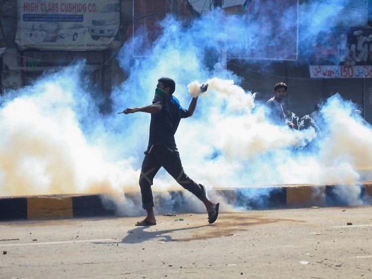 Demonstranten schleudern Tränengasbehalter auf Sicherheitskräfte in Lahore.