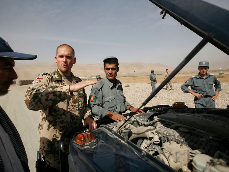 Ein Soldat der Bundeswehr erklärt afghanischen Polizisten, wie ein Fahrzeug durchsucht wird.