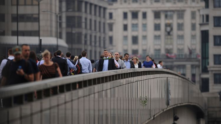 Pendler überqueren die London Bridge in Richtung Financial District in London.