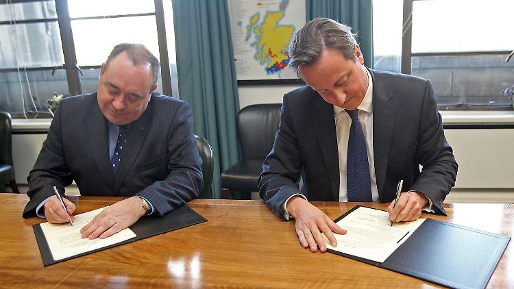 Alex Salmond und David Cameron setzen ihre Unterschrift unter das Dokument.